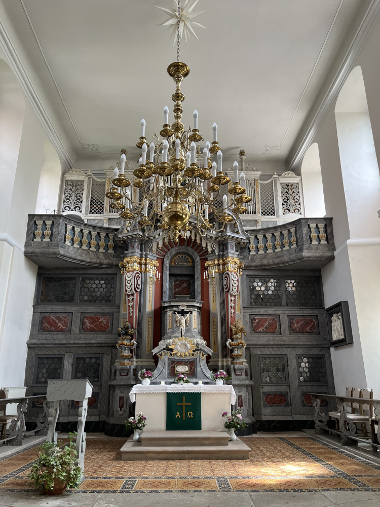 Blick in den Kirchenraum Richtung Osten, farbig marmorierter Kanzelaltar aus Holz mit geschwungenen Volutenkonsolen und Orgel auf einer geschwungenen Empore