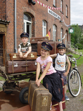 Kinder spielen vor dem Empfangsgebäude, im Hintergrund die alte Bahnhofsuhr